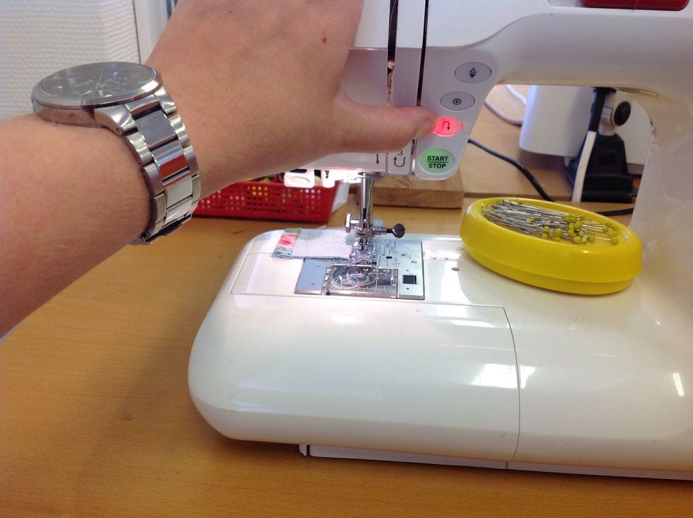 F\u00e4st i b\u00f6rjan och slutet genom att backa n\u00e5gra stygn. H\u00e5ll in backknappen s\u00e5 att den lyser r\u00f6tt medan du trycker ner pedalen med foten.