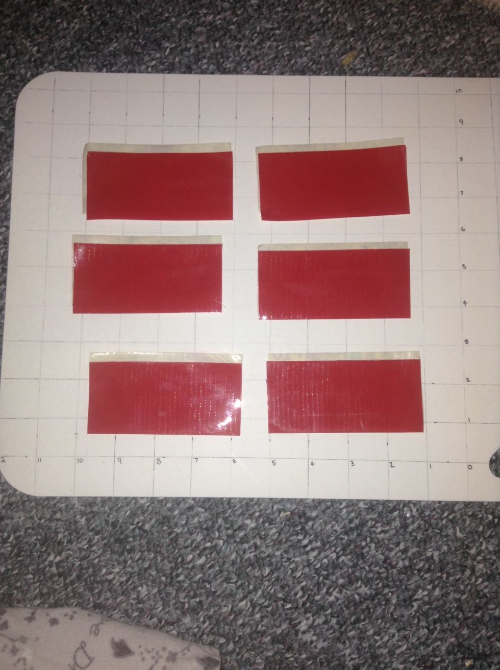 Face one of the pattern ones down with the sticky side up and place a red one on making sure there is a little space of tape showing on top.