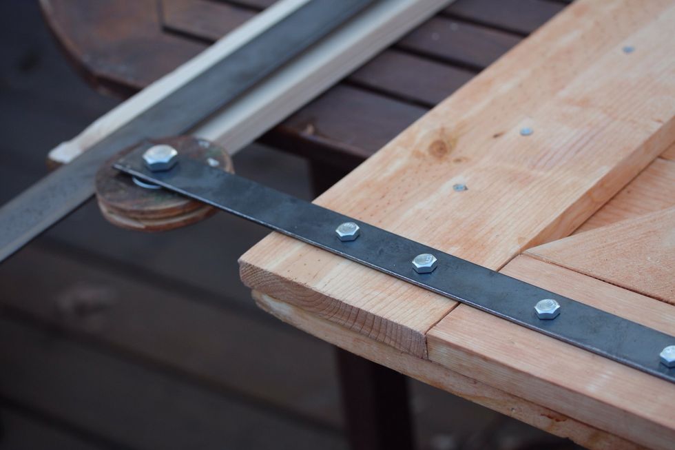 Fasten the left and right wheels to the door with 1inch wide steel. On the back side if the door use locking nuts to secure the steel . You can countersink the nuts in the back if you want them flush.