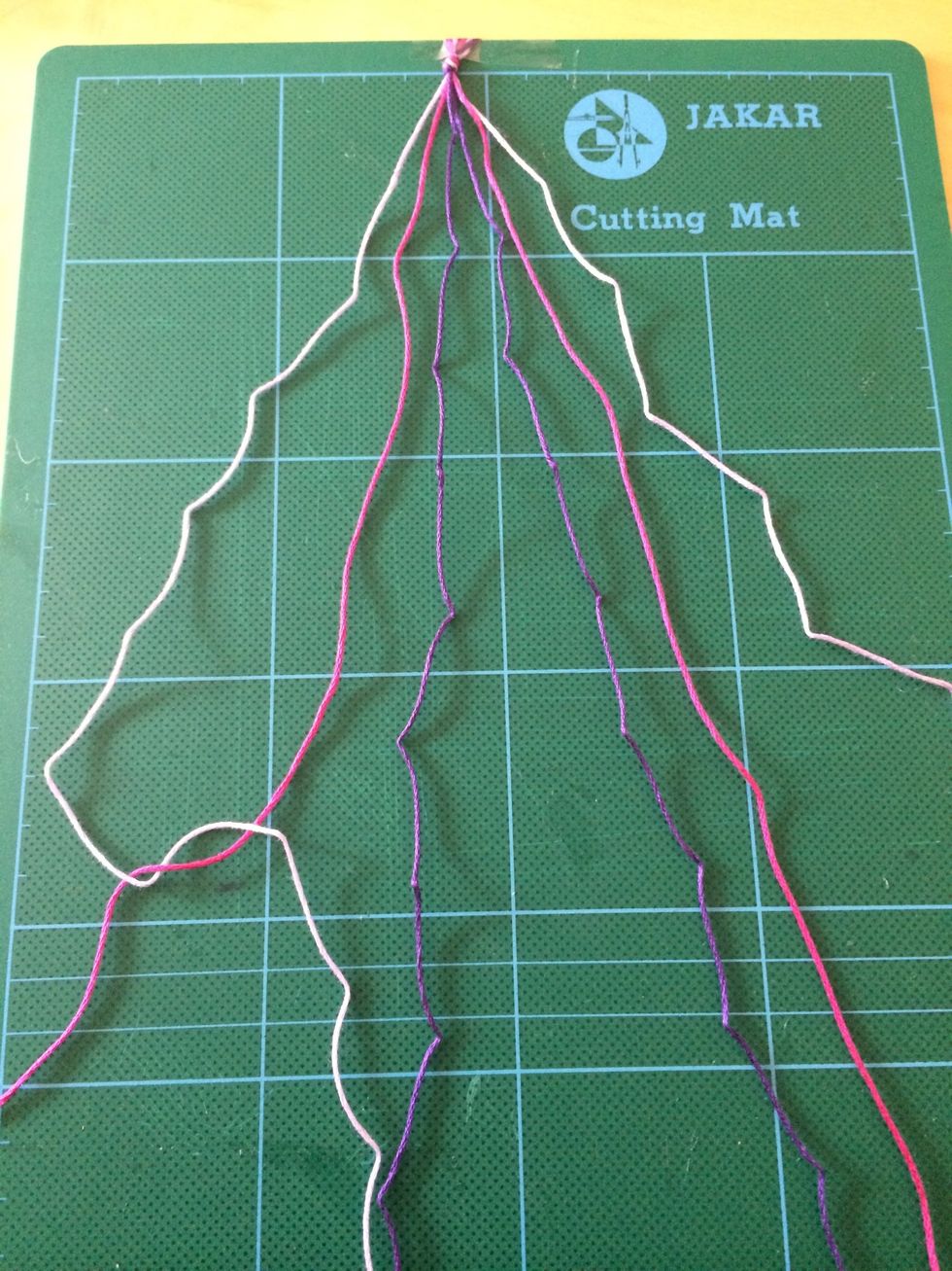 Feed the end of the lilac thread over the pink thread to make a loop and pull to the top to create a knot. Repeat it again to create a double knot on the same thread.