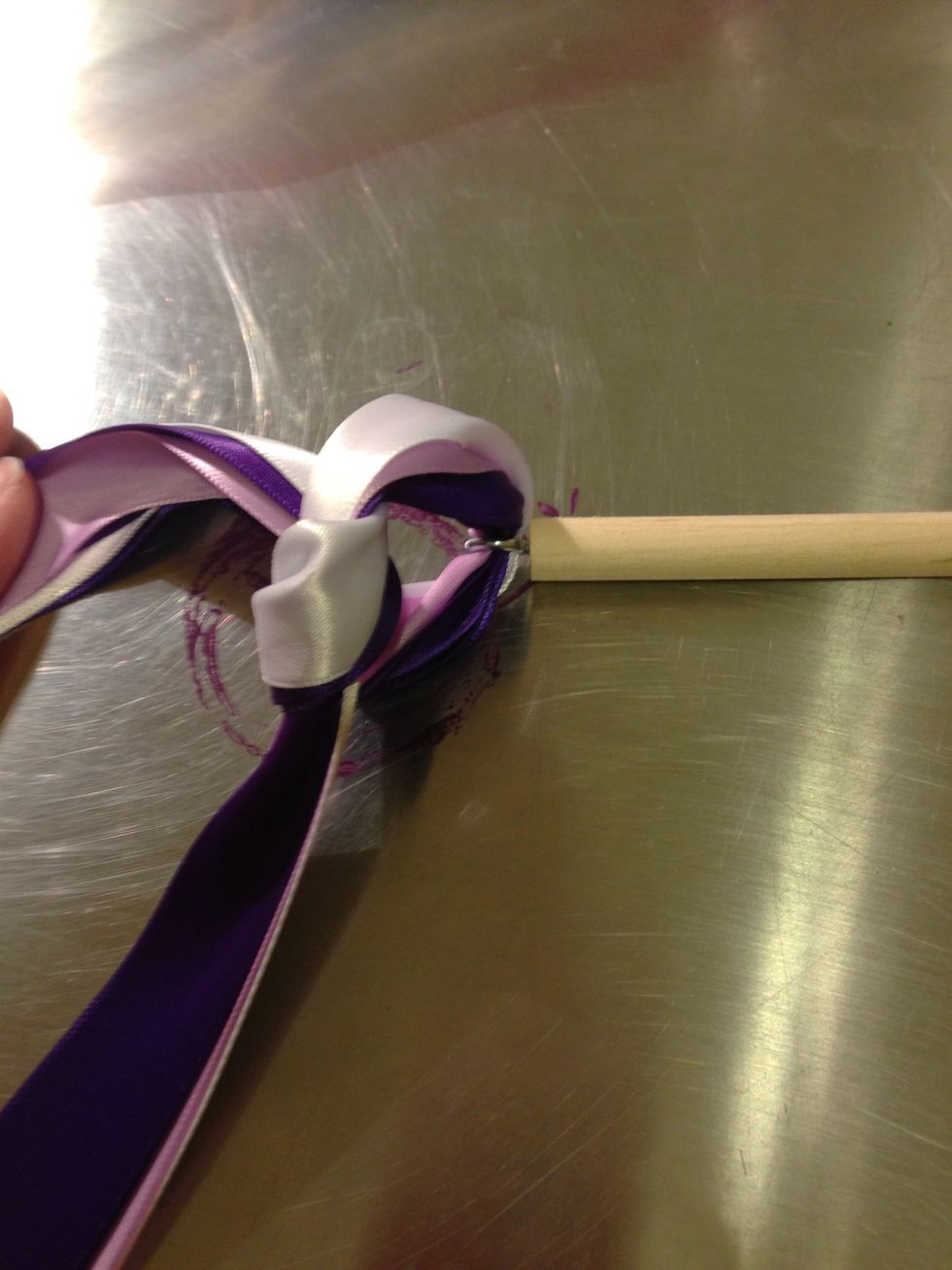 Feed your ribbon, one or two strands work best, through the eye. Tie a loose knot. Prep your hot glue gun.