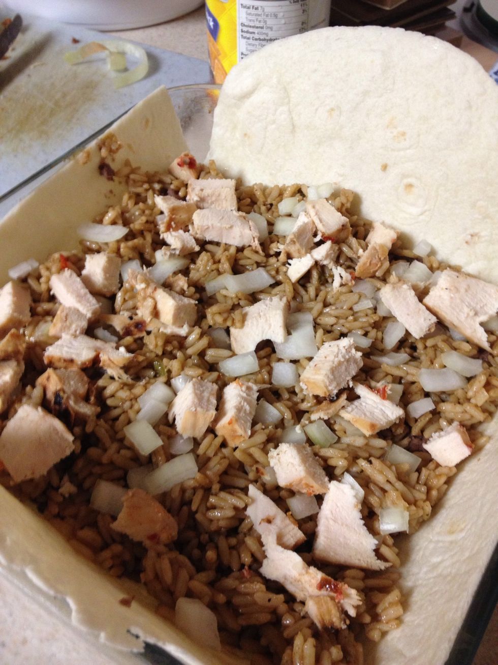 Fill the dish with ingredients. Line the bottom with refried black beans. Next cover with cooked rice. Add chopped tomatoes an chopped onions. Add chopped chicken breast. Cover with cheese.