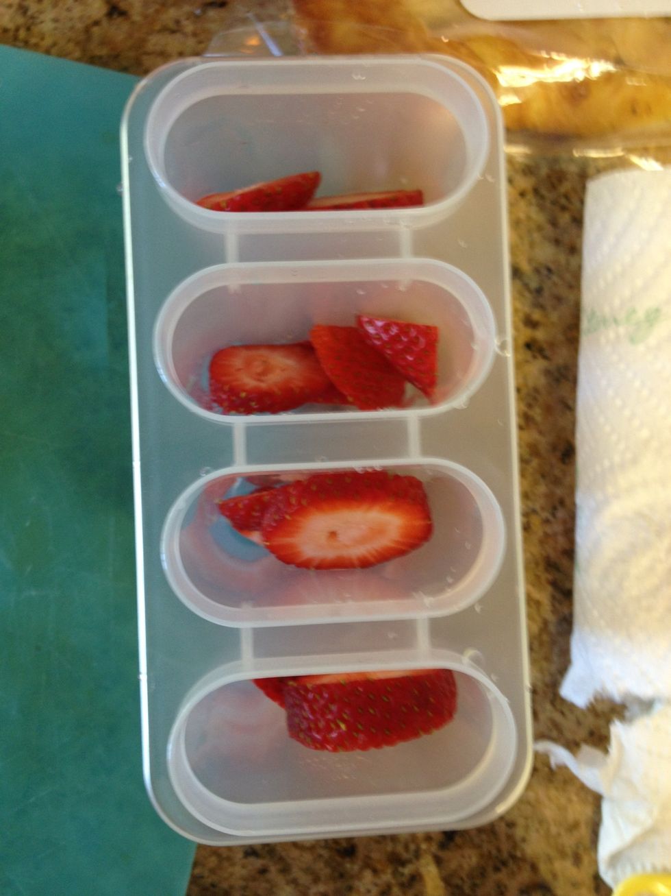 Fill the molds with fruit. Make sure not to fill the molds too high, because when we pour the juice in, the fruit will float to the top. (you can get the holders from any grocery store.)