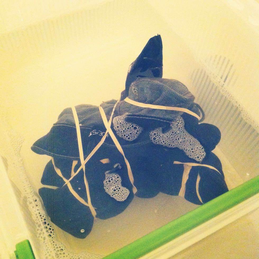 Fill the plastic container with cold water and use 1 part bleach with 2 parts water. I decided to use half a bottle of bleach. If your jeans aren't completely covered by the water, don't worry.