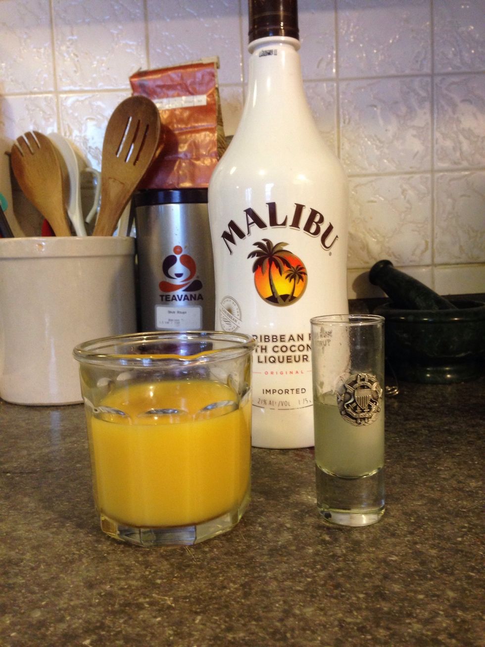 Fill the shot glass half full with Malibu rum.