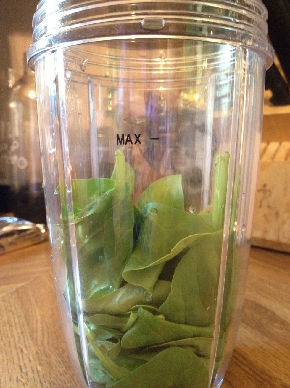 Fill up your NutriBullet half way with spinach. If you don't have a NutriBullet, you can use a blender, but it doesn't work as well.