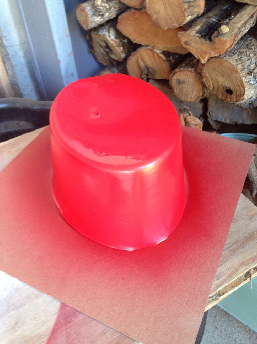 Find a spot outside protected by the wind and spray a coat of red paint evenly over hat.  Allow to dry.  Do this three to four times, allowing to dry between each coat.