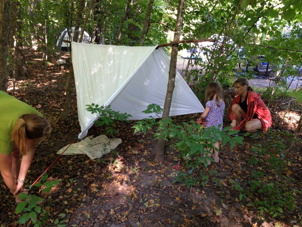 Find a sturdy straight branch and tie to two upright trees to support tent roof.