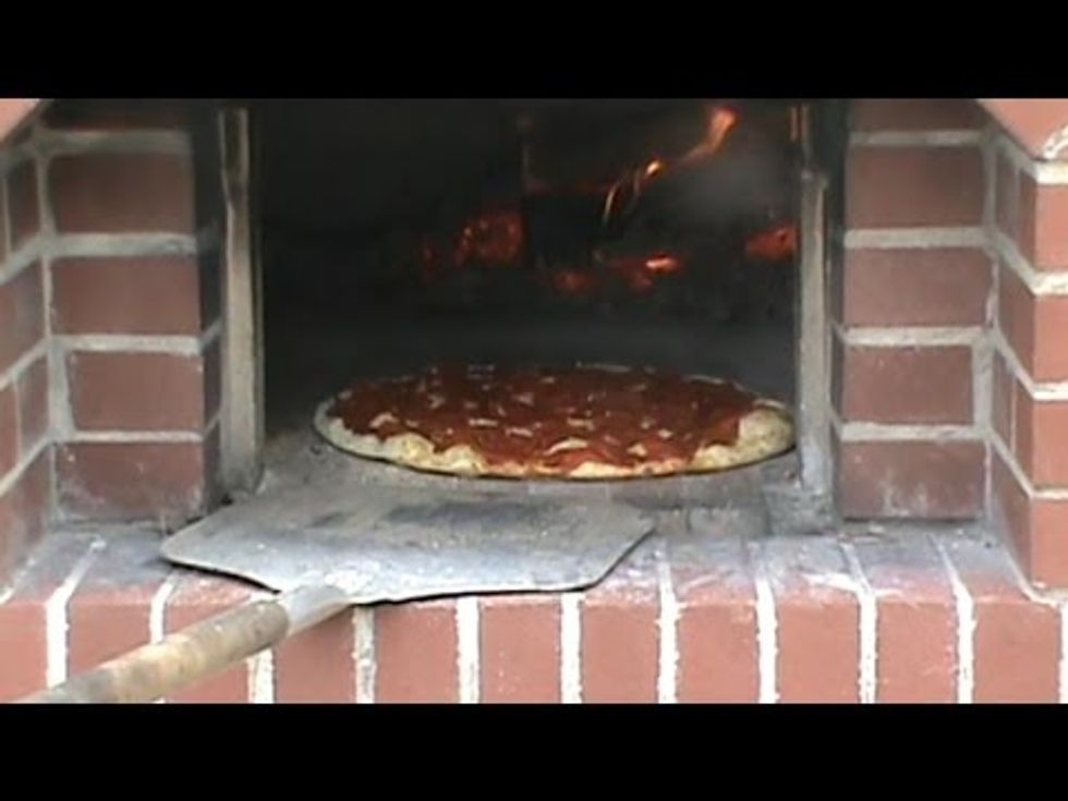 finish adding the pepperoni, then put the pizza on the pizza lifter. Put the pizza in the pizza oven {after you get the fire going} and let the pizza sit for a while. Wait for 20 minutes now.