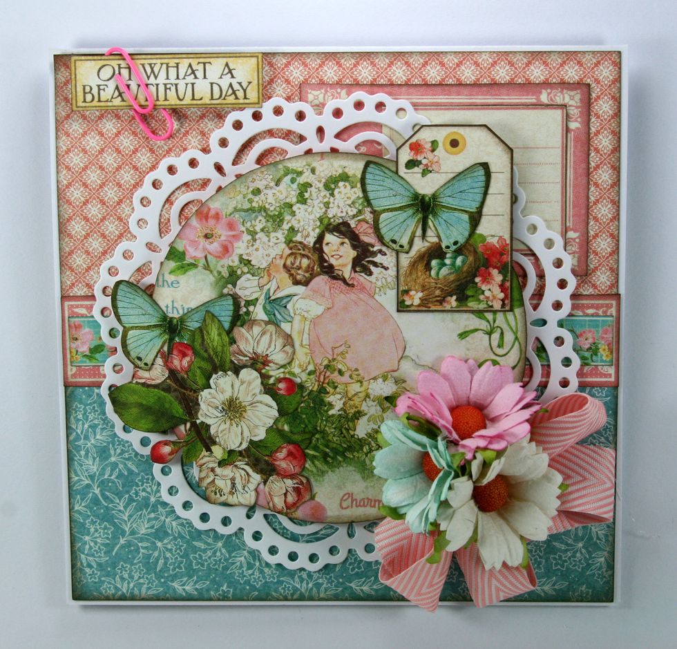 Finish off card with coordinating flowers and ribbon trim. Secure the sentiment tag with a pink clip and attach to top left corner of card.