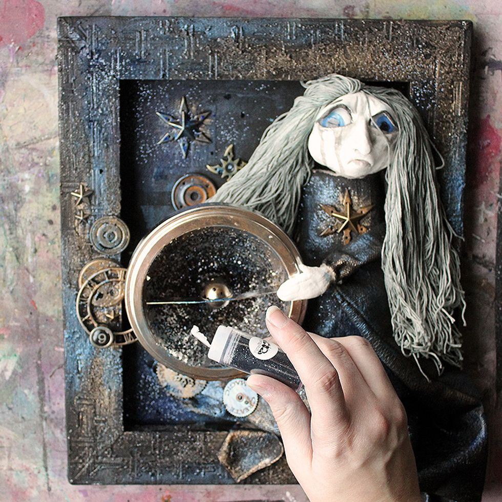 Finish the canvas with glitter. The glitter will stick to the paints/sprays on the canvas, but you can also use Soft Gloss Gel for a stronger hold. Just apply gel, then sprinkle glitter on top.