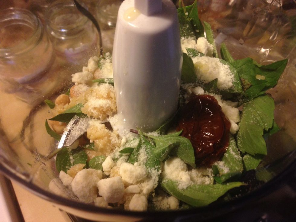 First, add your basil, garlic, cheese, tomato, and macadamia nuts into the food processor (or blender) then pulse it a bit to get things mixed up nicely!