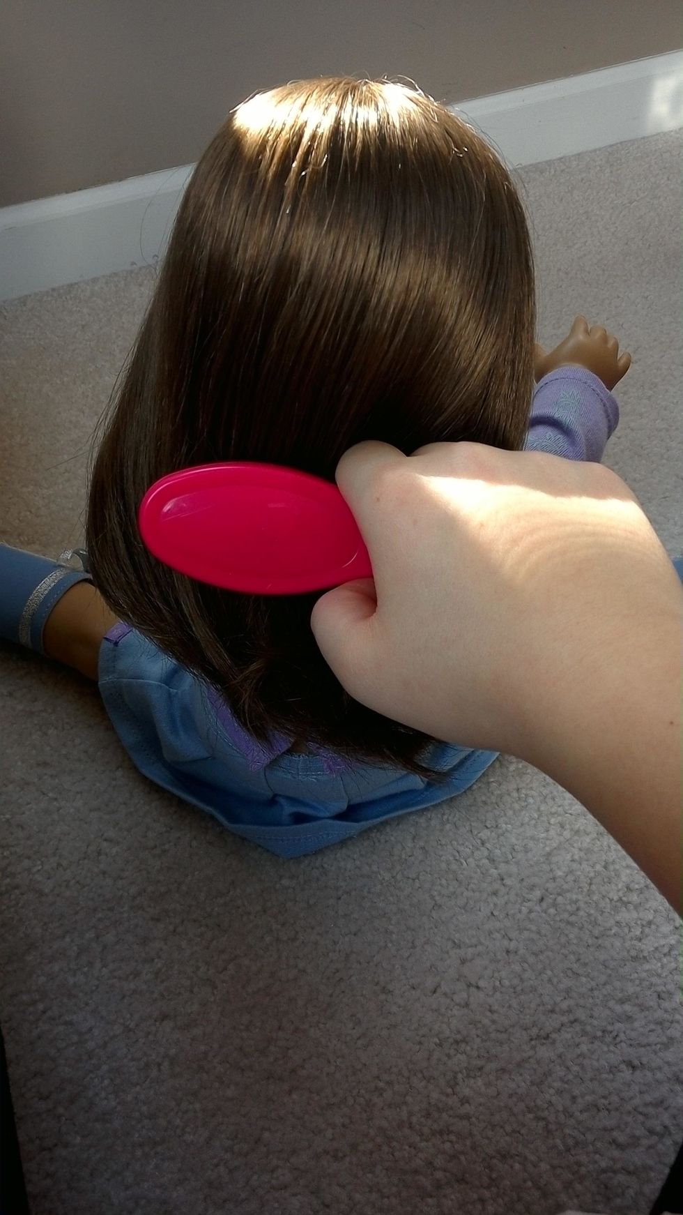 First, brush out your doll's hair using an American Doll brush. Work out any tangles.