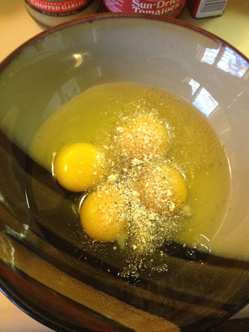 First, crack eggs into a bowl, then add black pepper, garlic salt, and garlic powder. Whisk.