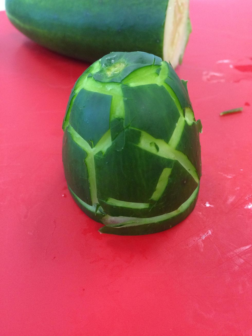 First cut a thin line close to the bottom of where you cut your cucumber. Next you have to cut an outline of a pentagon in the top and make your way down.