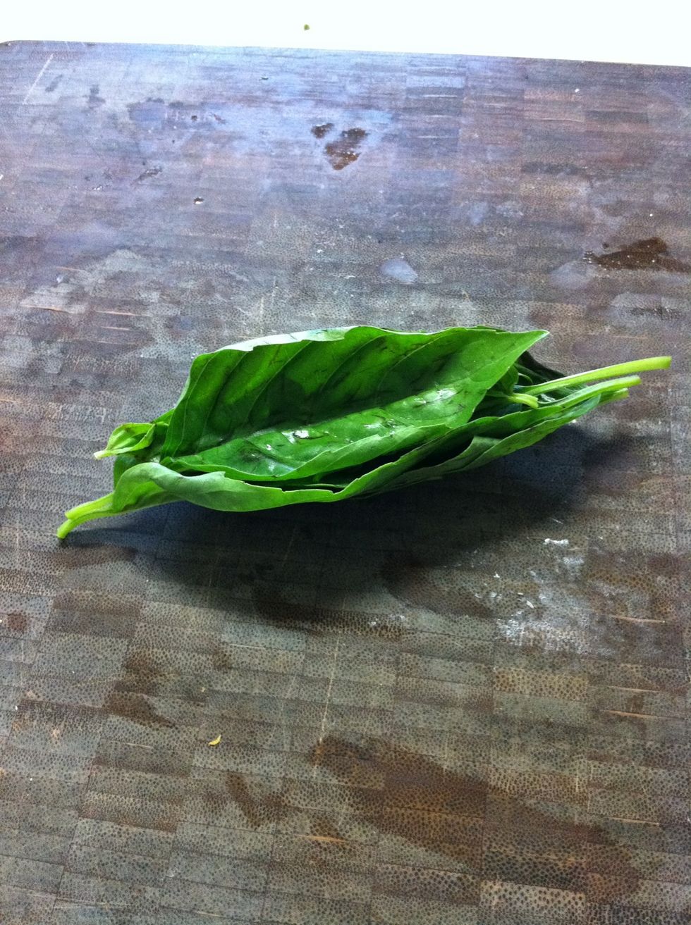 First, cut your basil. We're going to use a method called the "chiffonade cut." Stack your basil leaves on top of each other and roll like a cigar. Then use your knife to cut into thin strips.