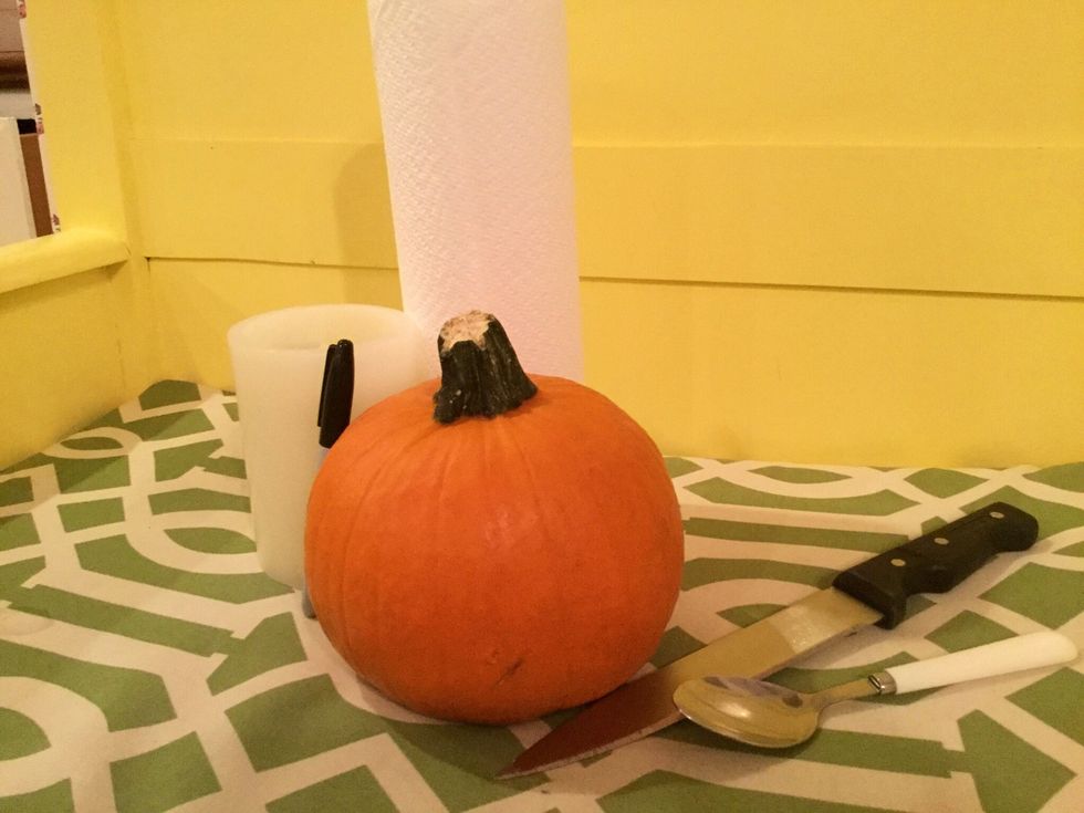 First gather your necessary supplies for carving a pumpkin. This includes a knife, spoon, paper towels, marker, candle and, of course, your pumpkin.