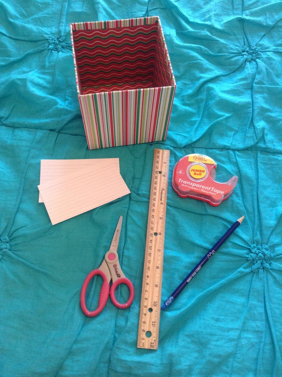 First, gather your supplies. You will need a tall box, 2 index cards, a ruler, tape, scissors, and a pencil.