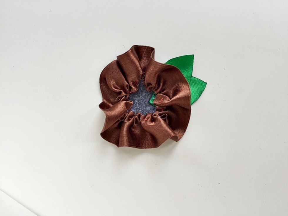 First, glue the leaves on the felt and then the large ruffled ribbon ring.