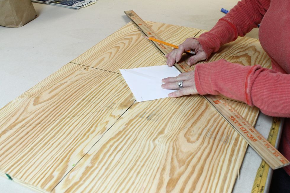 First I determined the middle of the plywood with a vertical and horizontal line. Then I cut a piece of paper the size I wanted the tufted squares and centered it diagonally on the board as shown.