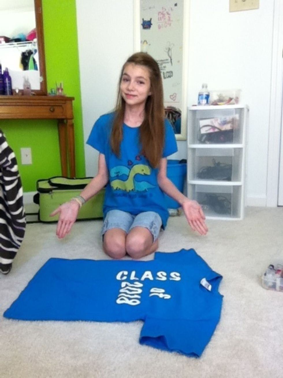 First, lay the shirt flat and sit to the side of it.