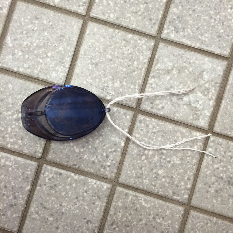 First, loop the nose piece string through one side of the goggles.