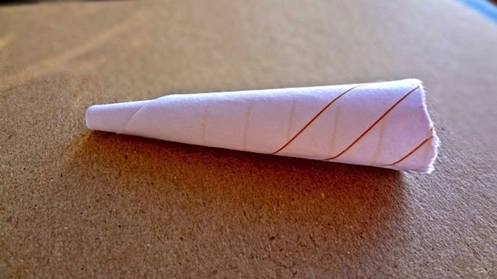 First make a small funnel by rolling your strip of paper like so. Secure it by wetting the loose end or use sticky tape.