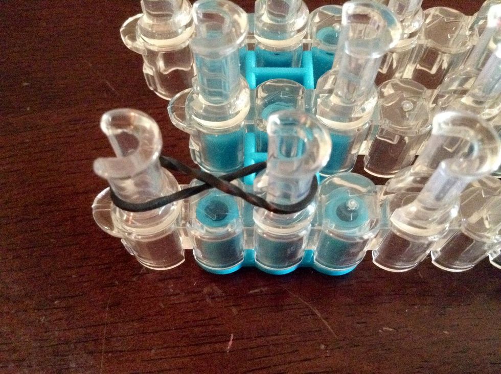 First, on the side of the rainbow loom, make a figure 8 by twisting the rubber band. and put it on 2 of the pegs