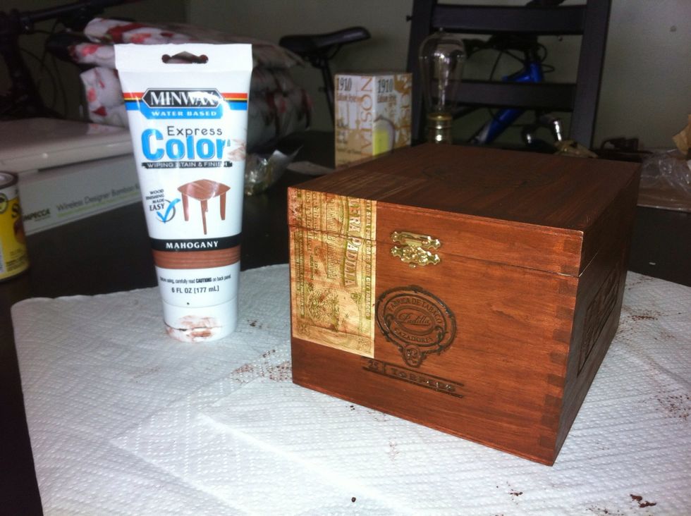First, pick a wood stain to cover the cigar box with. I chose a mahogany stain. Make sure to do this over newspaper so you don't accidentally stain your table! I wiped the stain on with an old rag.