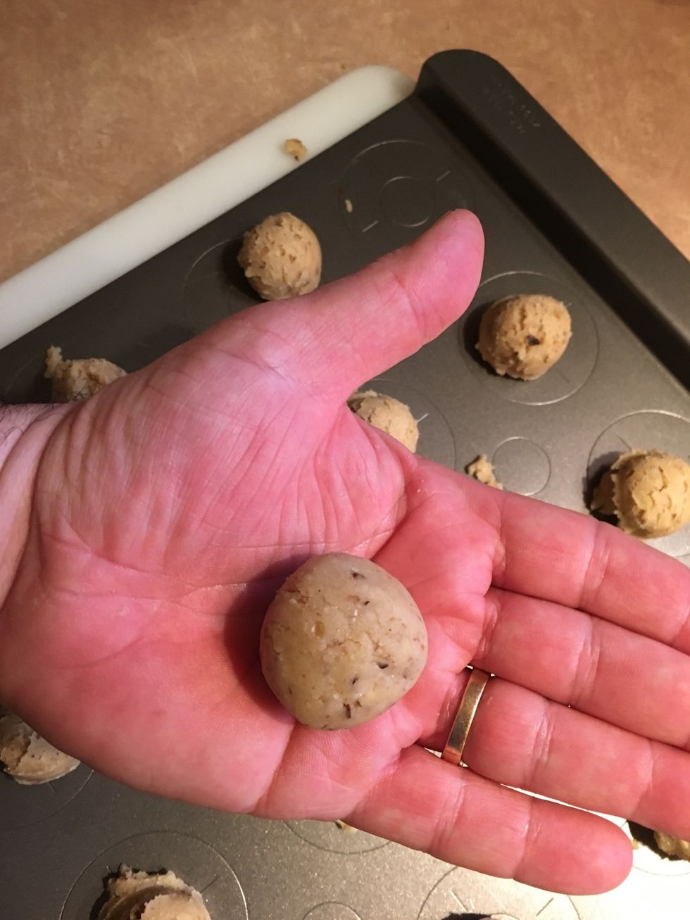First, place one piece of cookie dough between both palms. Use a rolling motion to shape into round balls.
