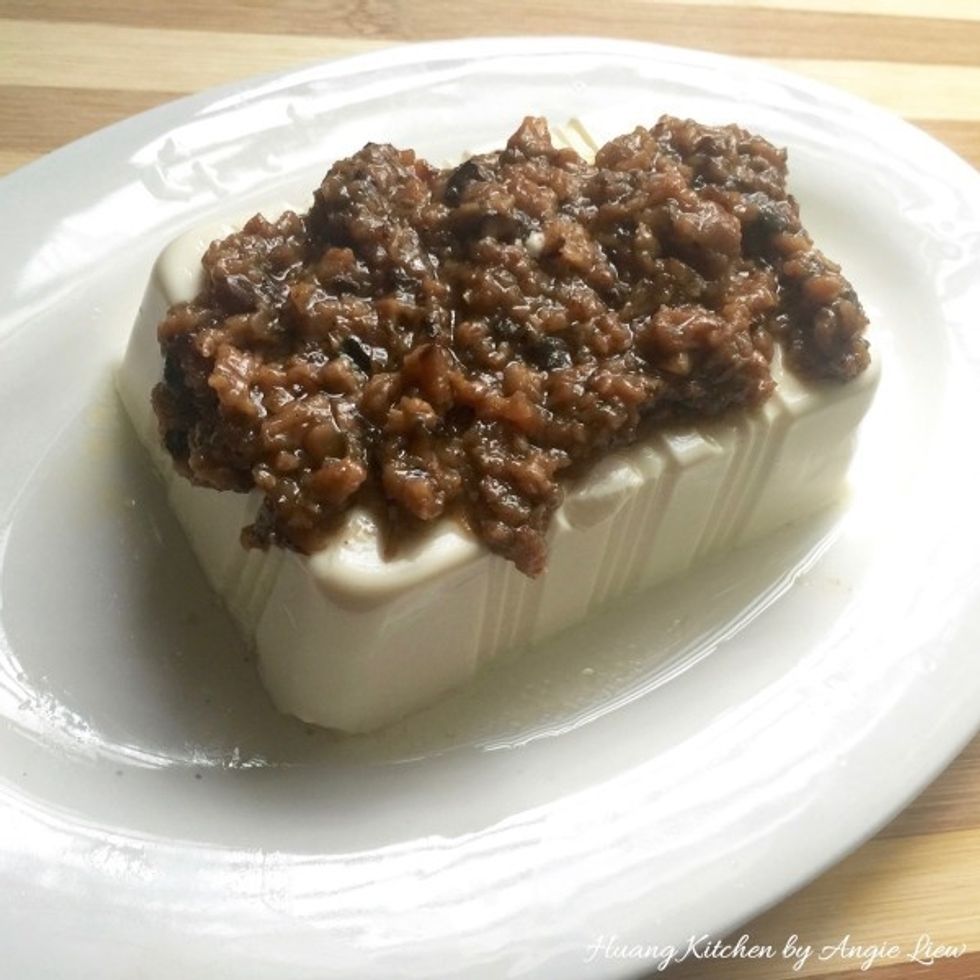 First, place the soft block of beancurd on a steaming plate. Pour the mushroom sauce onto the top of the beancurd.
