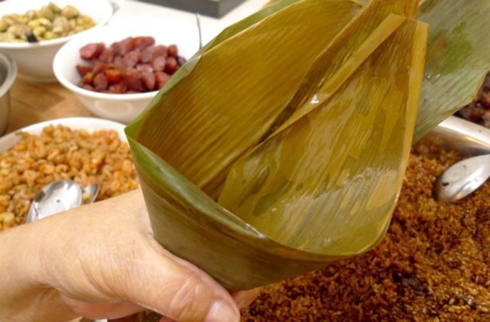 First select 2 bamboo leaves. Overlap them by 80% of the area. Starting at 1/3 lengthwise from one end, bend the leaves to form a cone making sure the smooth side of leaves is on inside of cone.