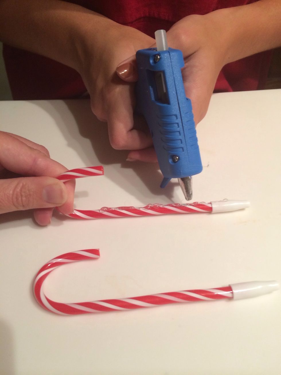 First set the two candy canes apart from each other on the table. Hot glue the top of the candy canes.