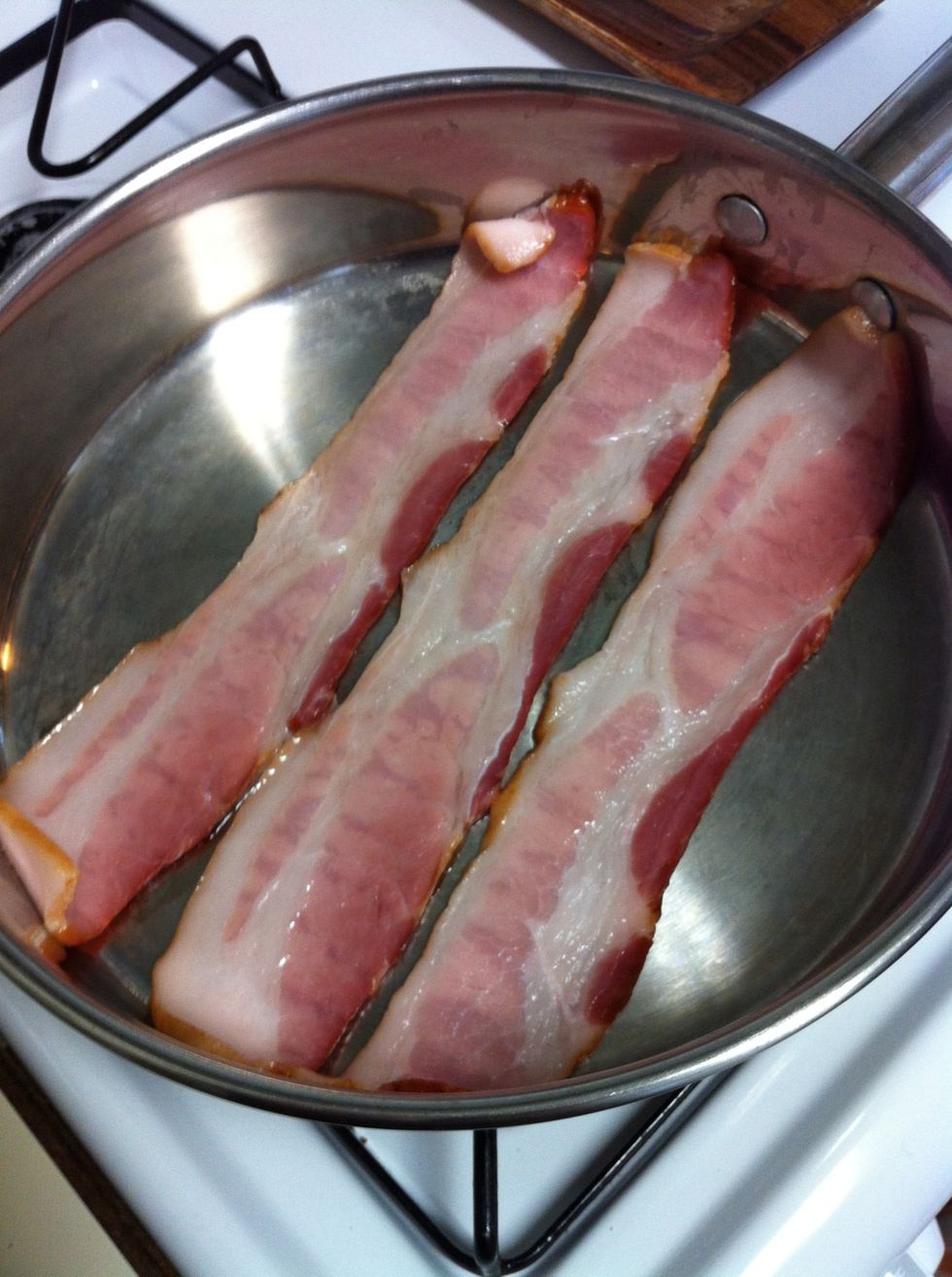 First, slow cook bacon on very low heat in a heavy bottomed pan. We are using a 10 inch stainless steel skillet. It's important to use very low heat so the bacon fat renders and caramelizes in the pan