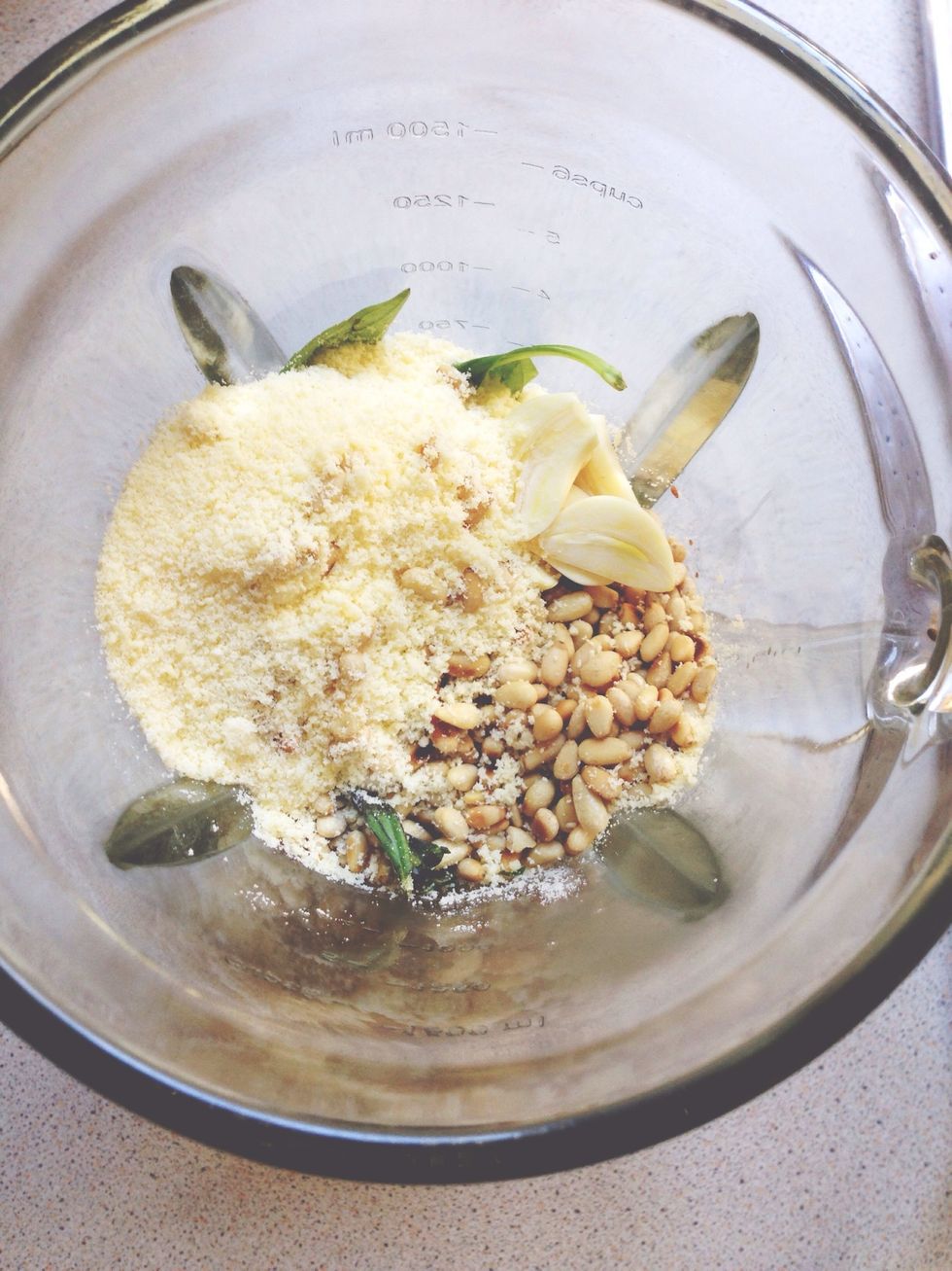 First step, make pesto. Add basil leaves, 2 cloves garlic, 3/4 cup Parmesan cheese, and 1/4 cup TOASTED pine nuts to food processor and blend.