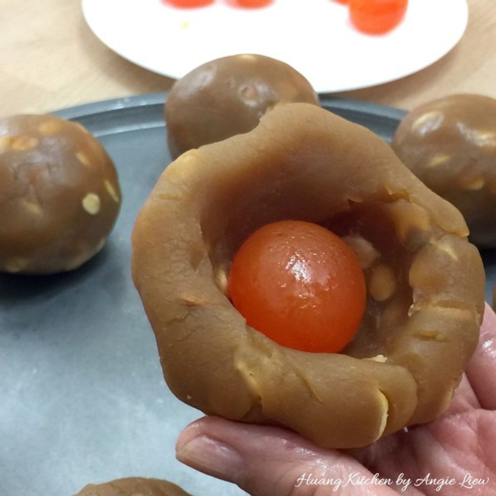 First, take a lotus paste ball and poke a hole in the middle with your finger. Place the baked egg yolk inside.
