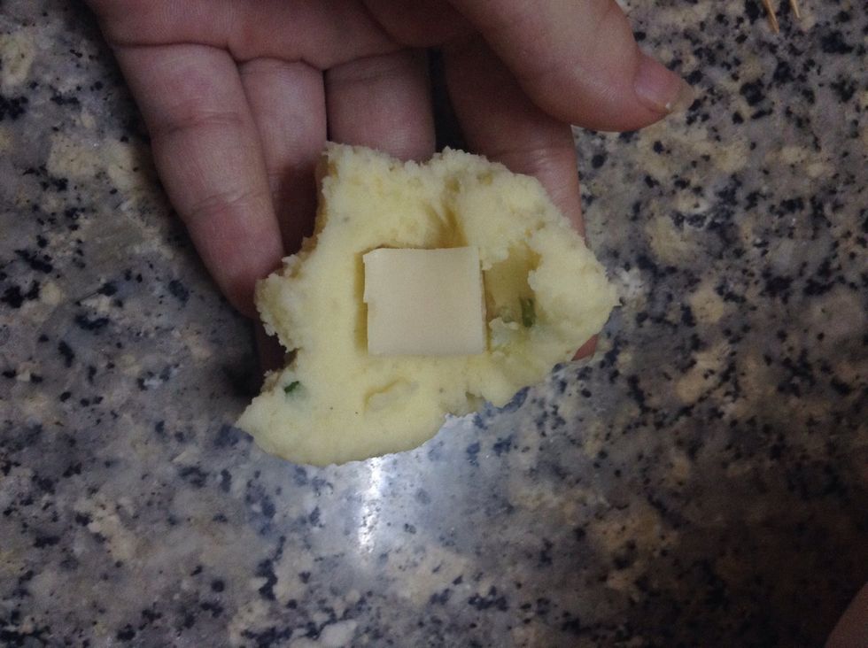 First, take a small chunk of mashed potato, put the cheese into the center and close it. The ball should be kinda thin that you can kinda feel the cheese inside, it will help the cheese melt easier.