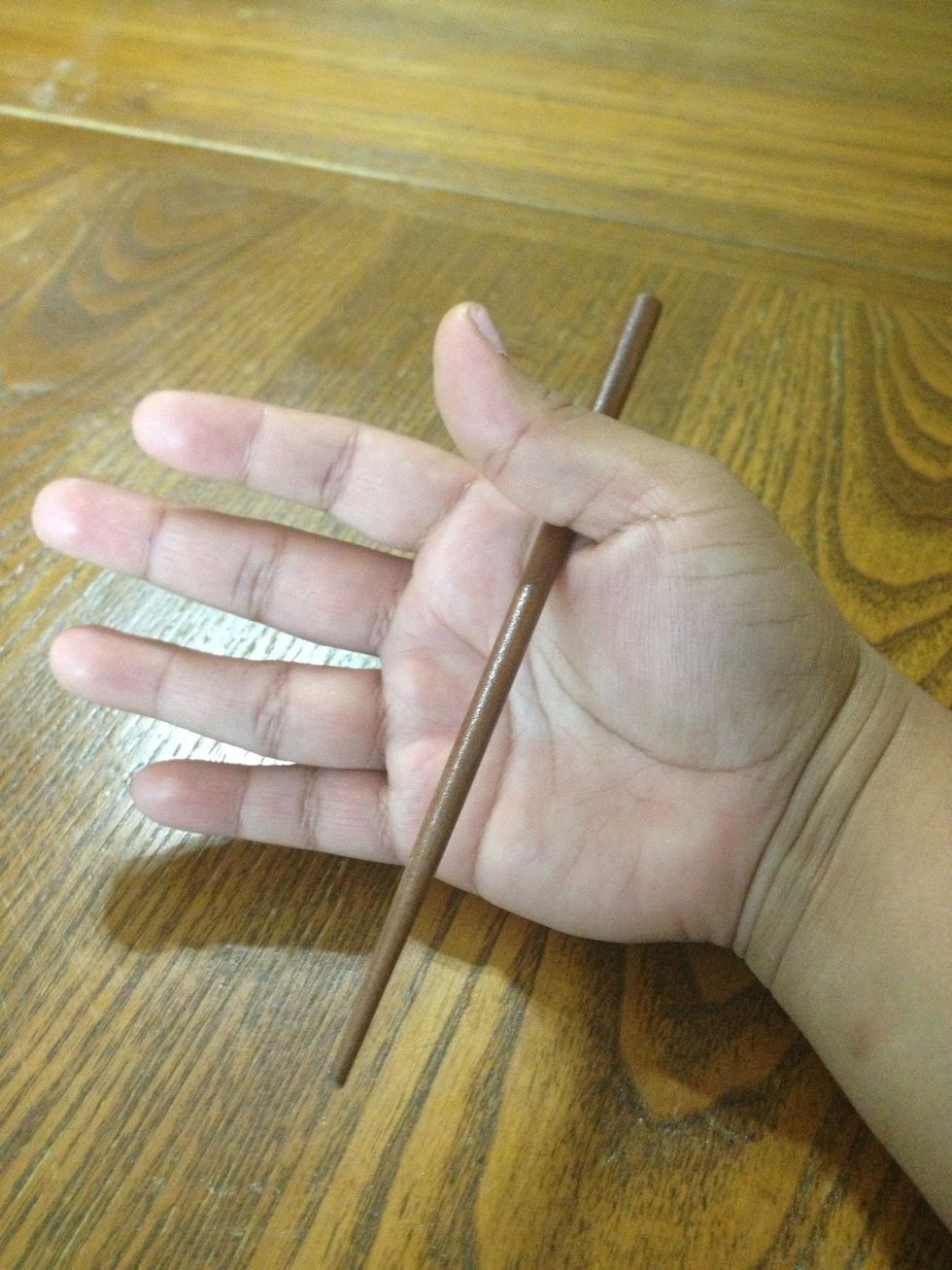 First take one chopstick and tuck it nicely in the web of your thumb. Depending on the length of the chopstick or however you feel comfortable holding it, about 1/3 down the chopstick is a good start.