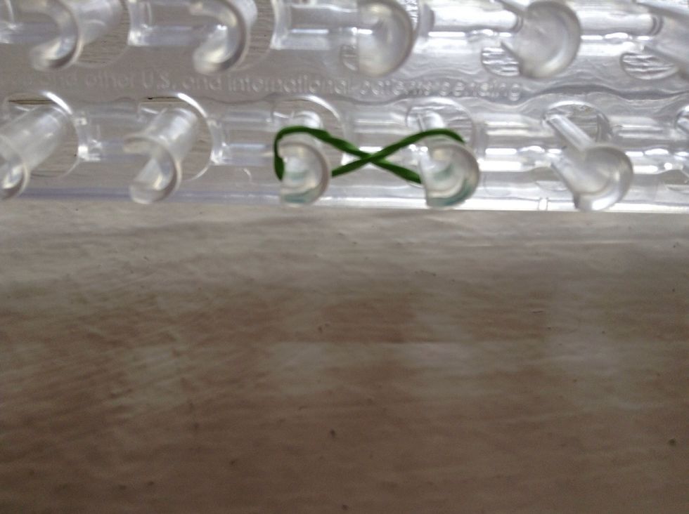 First, take your rubber-band and twist your rubber-band into an infinity sign. And place it on two pegs.