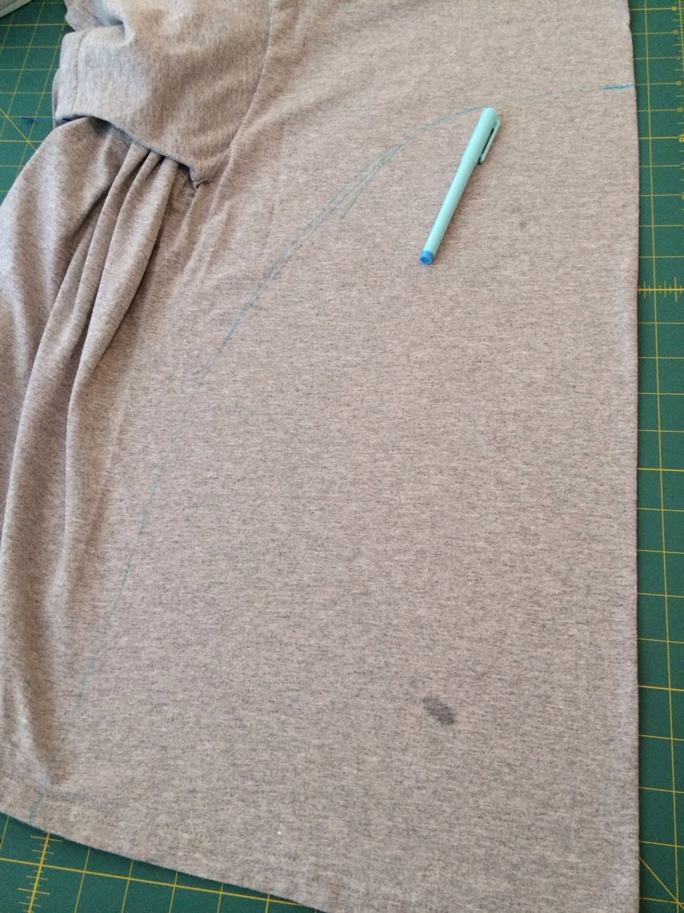 First, try on the shirt and mark where the belly should be. Then, take one side of the light grey t-shirt and fold it down the middle. Draw a gentle arch between your marks.