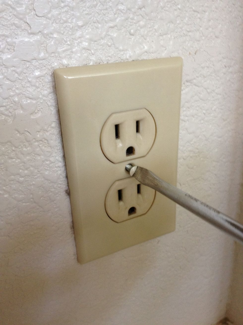 First use the flathead screwdriver to remove the receptacle's cover plate. You'll notice I refer to this electrical device as a receptacle, plug, or outlet - the terms are pretty interchangeable.