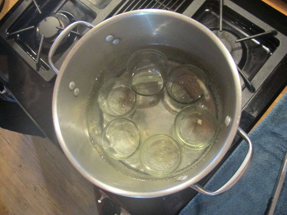 First wash jars and lids with hot soapy water. Then sterilize by placing them in boiling water for about 3 min. Place on a clean towel to dry.