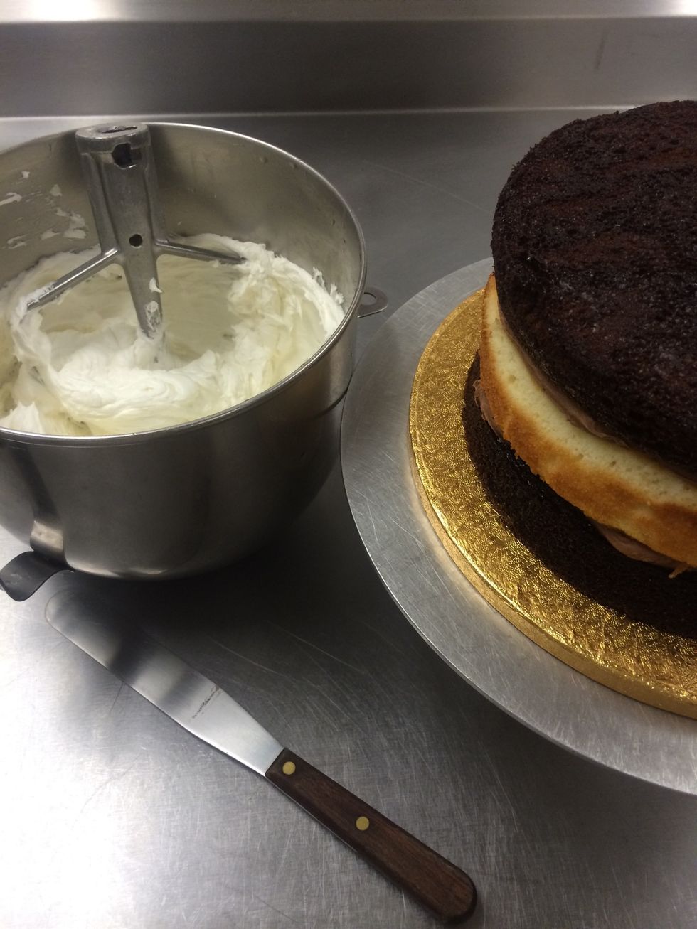 First, we're going to crumb coat  the cake. Crumb coat is a very thin coating of frosting to hide seams in the cake and to cover and have all the crumbs stick so they can not be seen in the fondant.