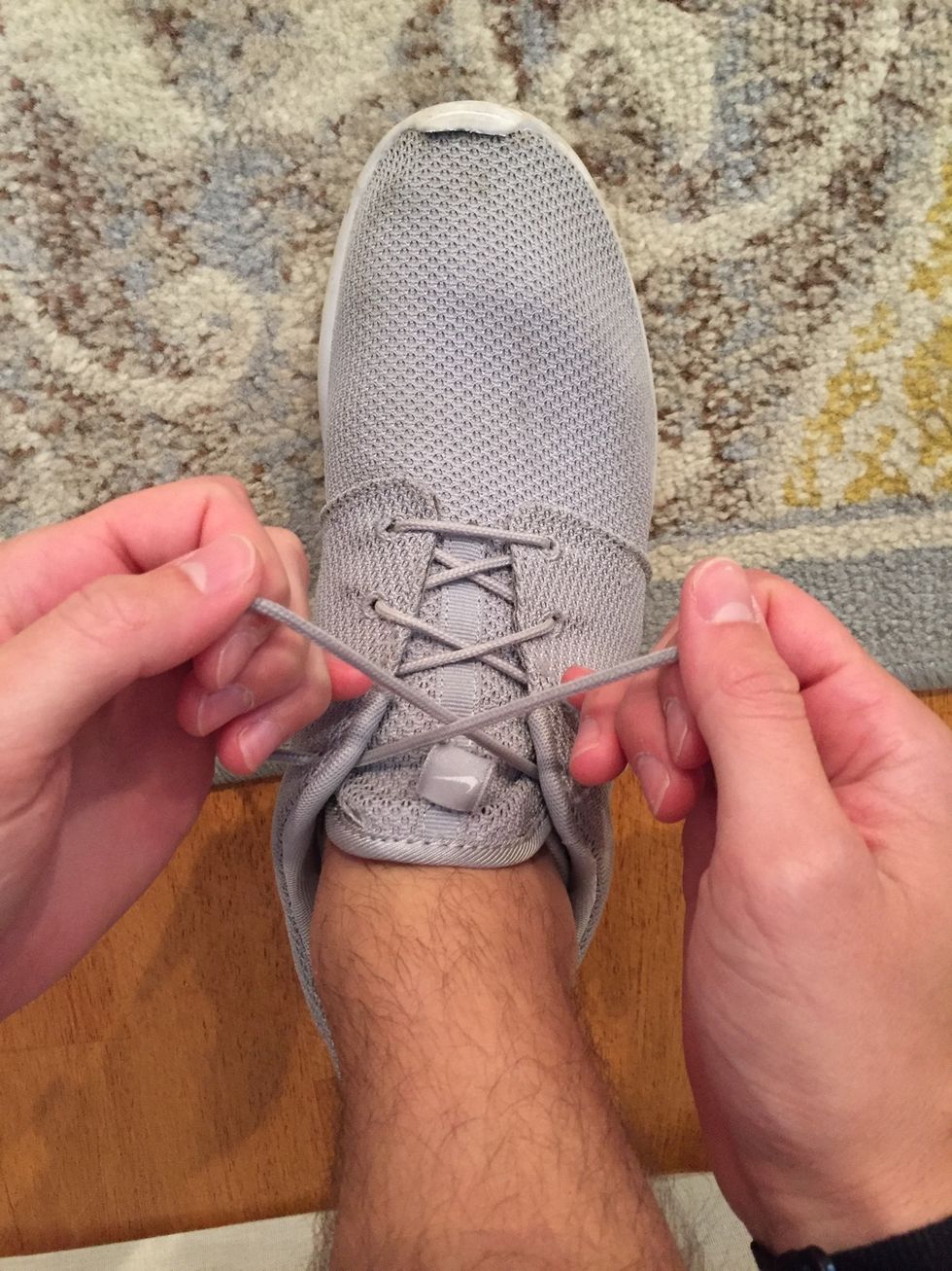 First, you want to tighten all of the laces by grabbing the second-to-top two strings and pulling them toward you without pulling the laces out of the holes