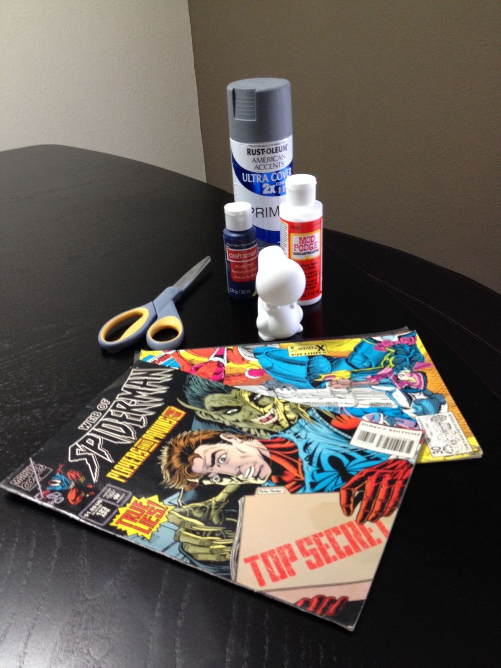 First you will need to gather your supplies: blank vinyl toy, scissors, mod Podge glue, old comic books, primer (optional), acrylic paint (optional)