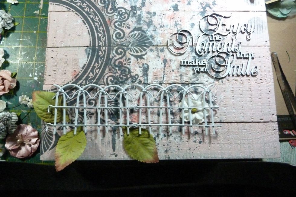 Fix the chipboard title on right hand side. I used a metal fence from previous kit as a base to my flower cluster & started placing base flowers and leaves.
