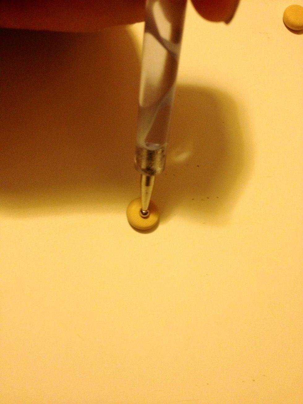 Flatten it down a bit with your finger, then poke a hole through the middle.