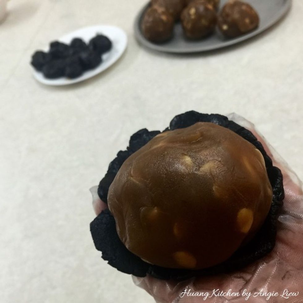 Flatten slightly the dough skin and wrap it around the lotus seed paste filling by slowly pushing the dough skin until totally cover the entire lotus paste filling.