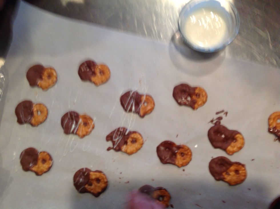 Flick the white chocolate on the dry chocolate covered pretzels with a spoon.