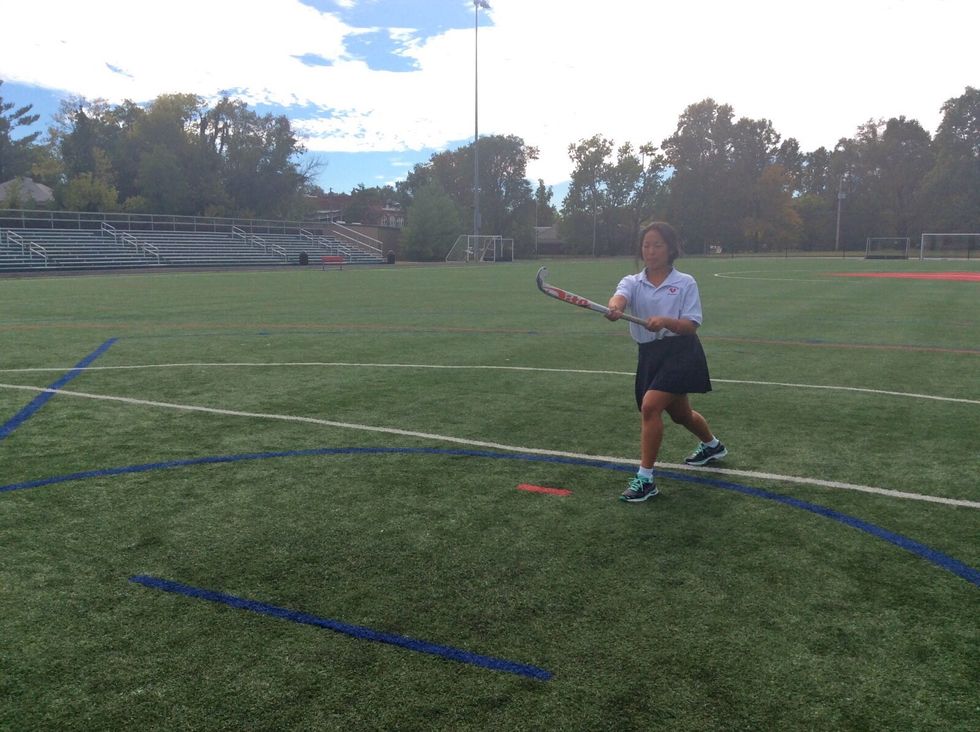 Flick your stick, while pushing the ball. This will elevate the ball into the air.